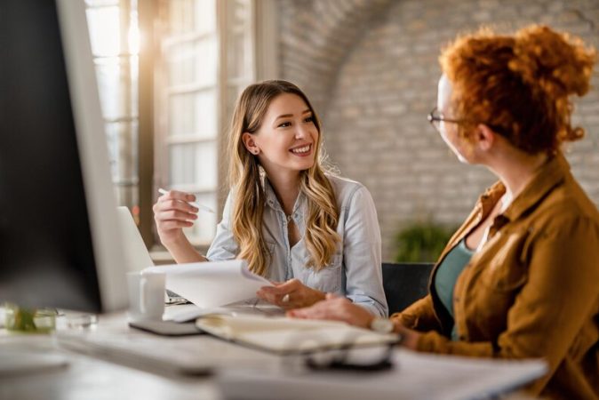 [fpdl.in]_empresaria-criativa-sorridente-passando-pela-papelada-e-conversando-com-sua-colega-no-escritorio_637285-1974_medium
